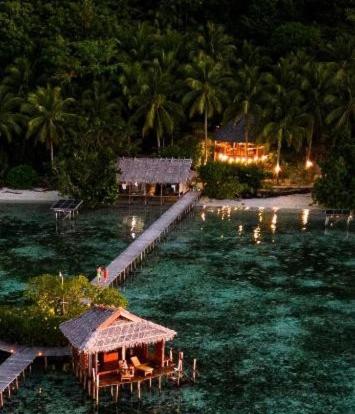 Nyande Raja Ampat homestay dengan bungalow kayu di atas laut dan pemandangan pulau karst
